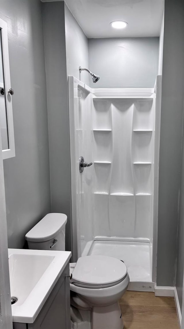 bathroom featuring toilet, vanity, hardwood / wood-style floors, and a shower