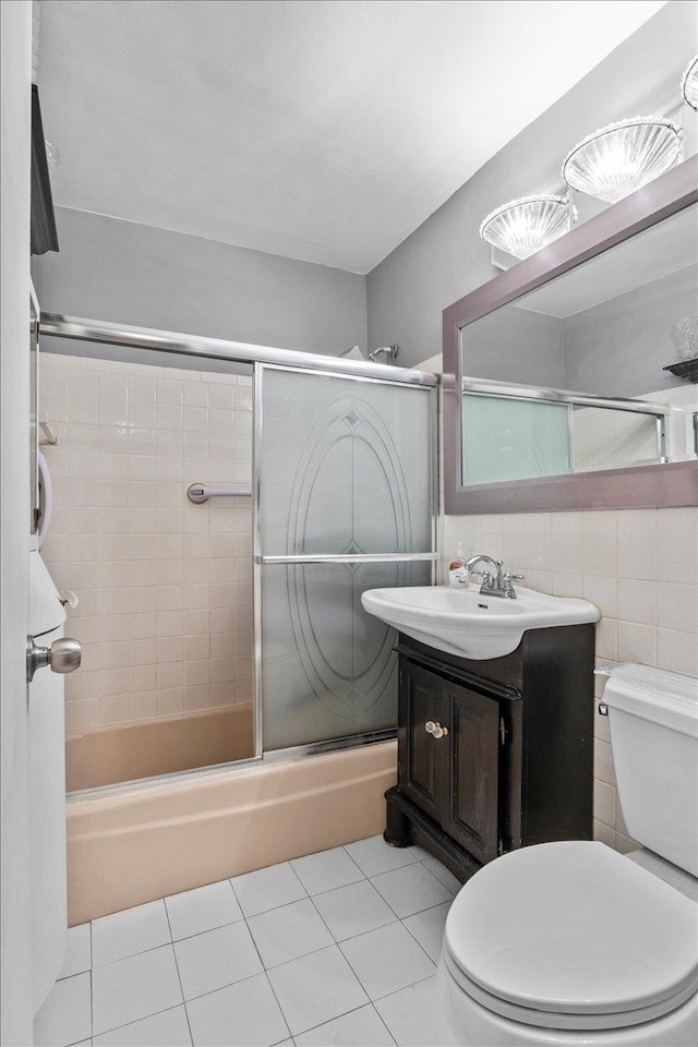 full bathroom with tile patterned floors, toilet, tile walls, vanity, and bath / shower combo with glass door