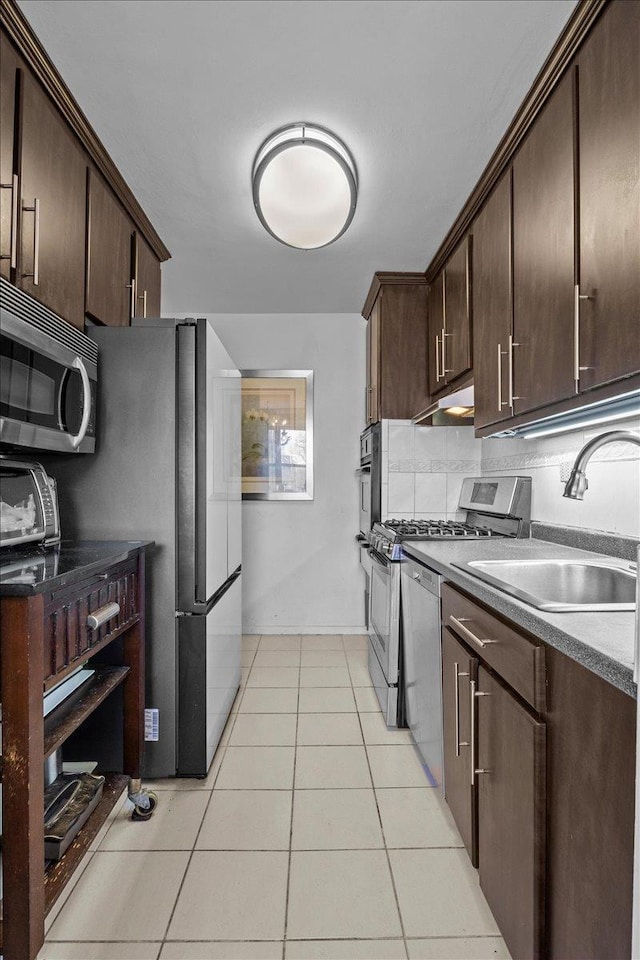 kitchen with dark brown cabinetry, appliances with stainless steel finishes, sink, and light tile patterned flooring