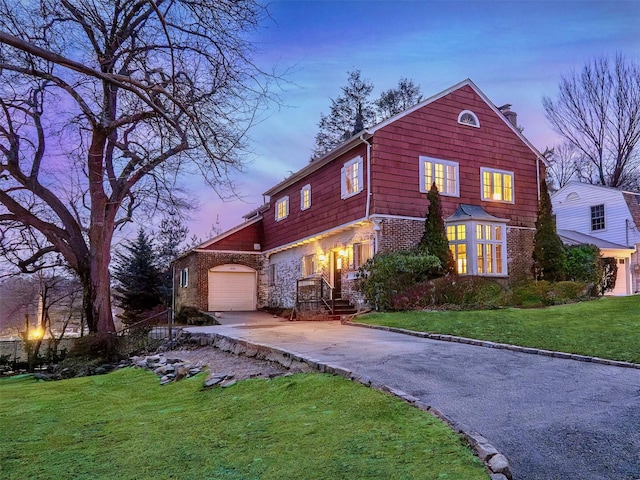 view of front of home featuring driveway, a front yard, a chimney, and brick siding