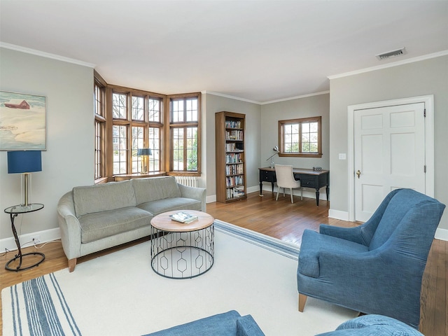 living area featuring visible vents, wood finished floors, and ornamental molding