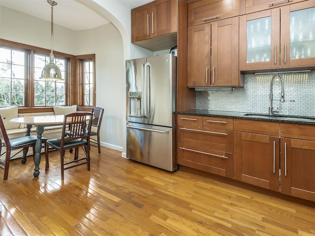 kitchen with stainless steel fridge, brown cabinetry, and a sink