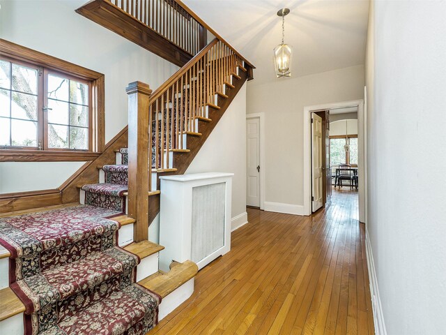 stairway featuring a notable chandelier, wood-type flooring, and baseboards