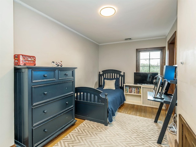 bedroom featuring ornamental molding, visible vents, and light wood-style flooring