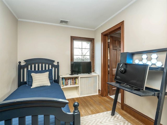 bedroom with wood finished floors, visible vents, and crown molding