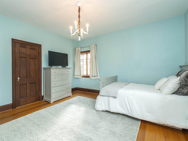 bedroom featuring a notable chandelier, baseboards, and wood finished floors