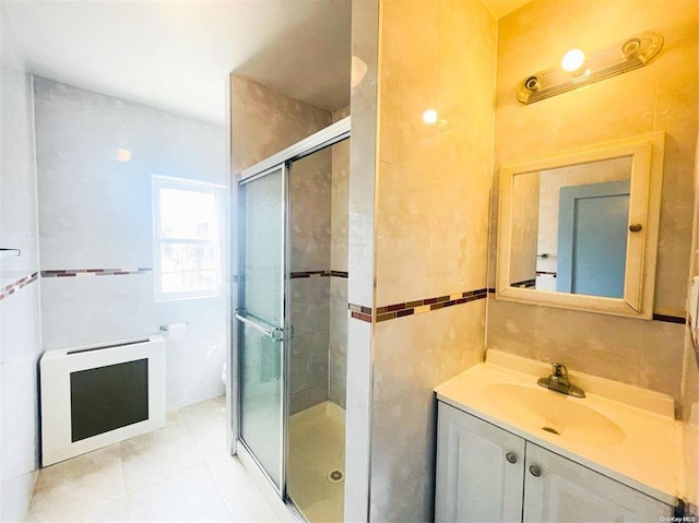 bathroom featuring tile walls, vanity, walk in shower, tile patterned flooring, and heating unit