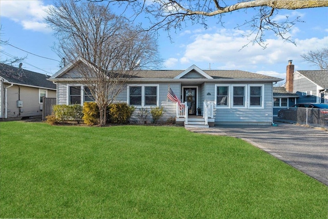 ranch-style home with aphalt driveway, a front yard, and fence