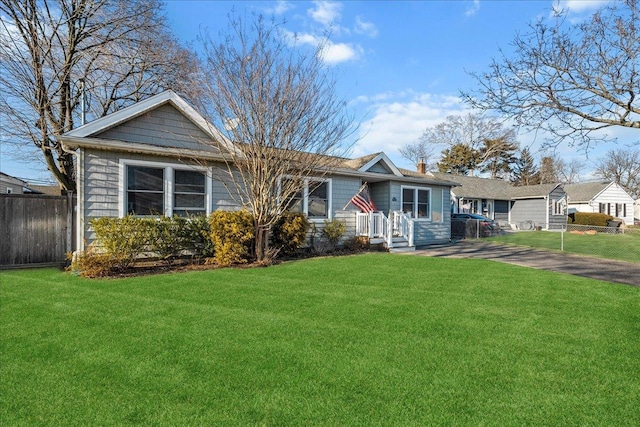 ranch-style house featuring a front lawn, a chimney, and fence