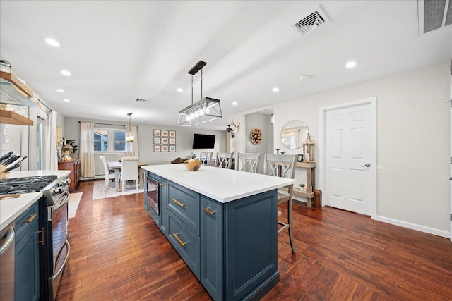 kitchen with blue cabinetry, visible vents, stainless steel appliances, and a breakfast bar area