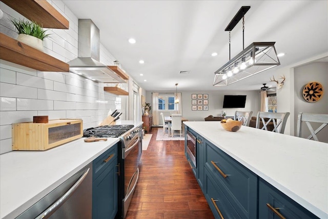 kitchen with decorative backsplash, wall chimney exhaust hood, appliances with stainless steel finishes, blue cabinetry, and open shelves