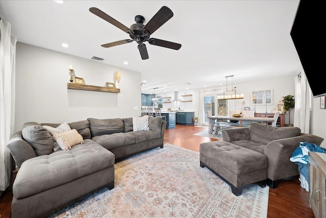 living room with ceiling fan with notable chandelier, visible vents, wood finished floors, and recessed lighting