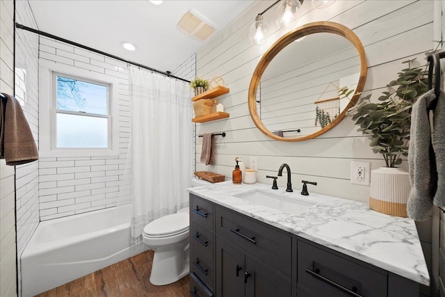 bathroom with visible vents, toilet, wood finished floors, shower / bath combination with curtain, and vanity