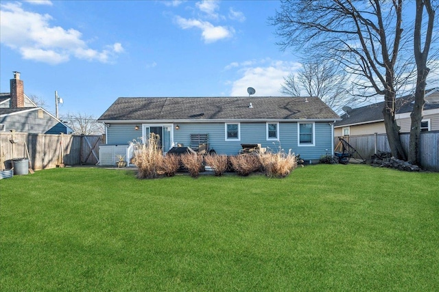 rear view of house with a fenced backyard, a shingled roof, a patio, and a yard