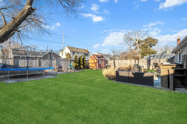 view of yard featuring a trampoline, an outbuilding, a storage unit, an outdoor hangout area, and a fenced backyard