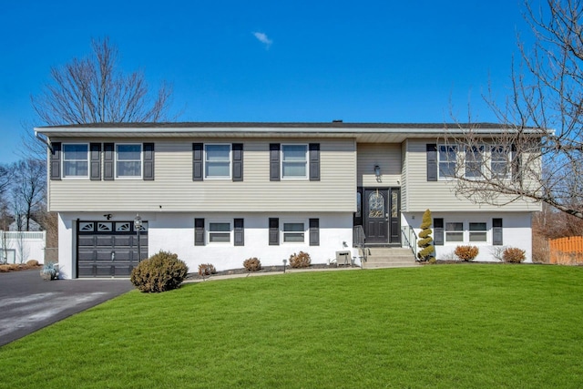 split foyer home featuring a garage, aphalt driveway, and a front yard