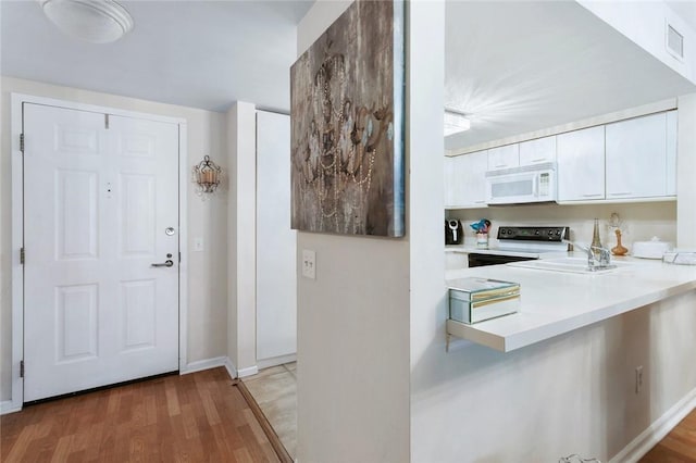 kitchen featuring range with electric stovetop, white cabinetry, hardwood / wood-style flooring, and sink