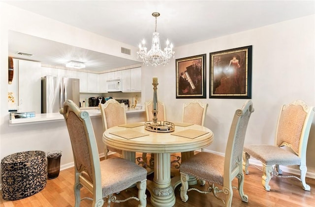 dining room featuring light wood-type flooring and a notable chandelier