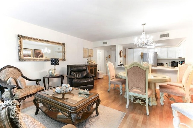 living room with light hardwood / wood-style floors and an inviting chandelier