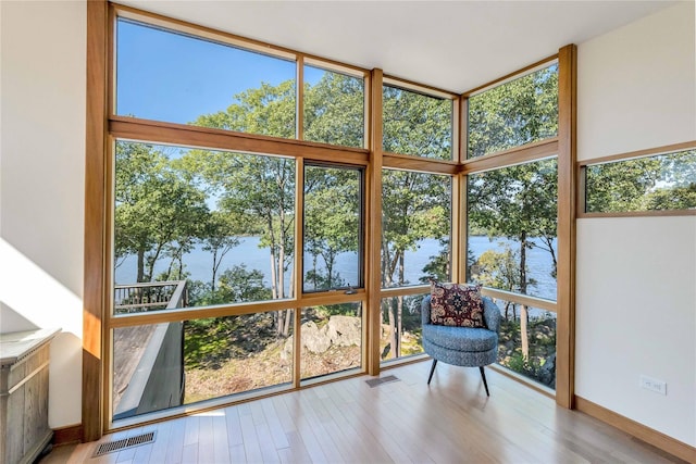 unfurnished sunroom with a water view, visible vents, and a wealth of natural light