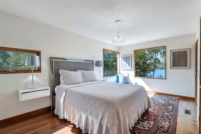 bedroom with dark wood-style floors, visible vents, and baseboards