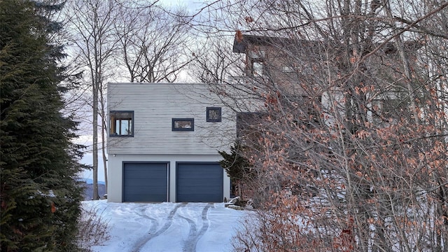 view of snow covered exterior with an attached garage and stucco siding