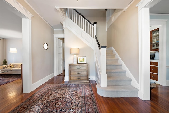 stairway featuring baseboards, ornamental molding, and wood finished floors