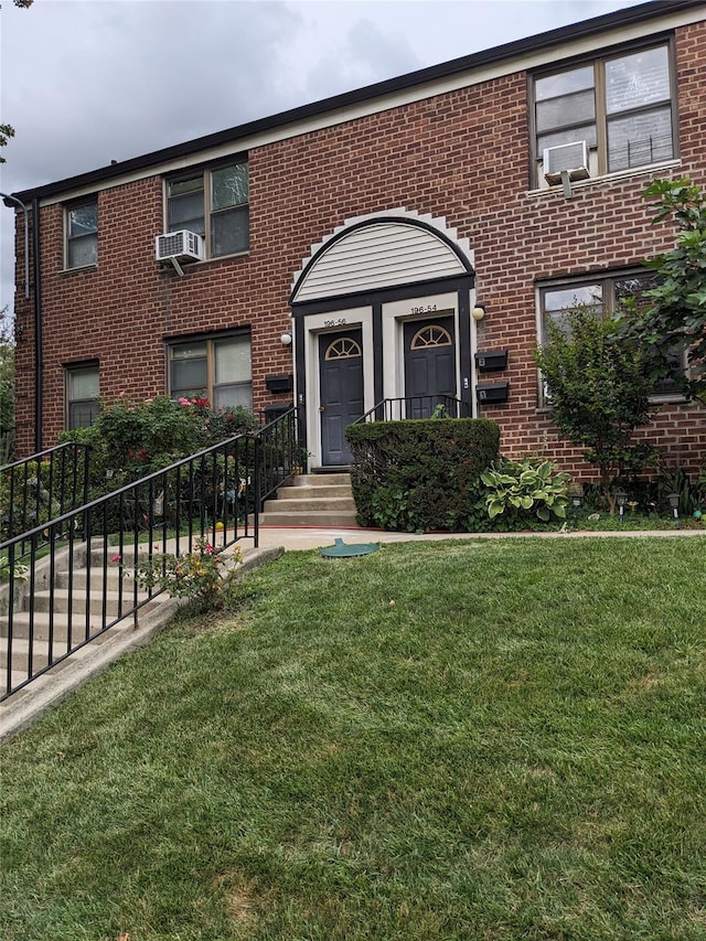 view of front of house featuring brick siding, a front lawn, cooling unit, and fence