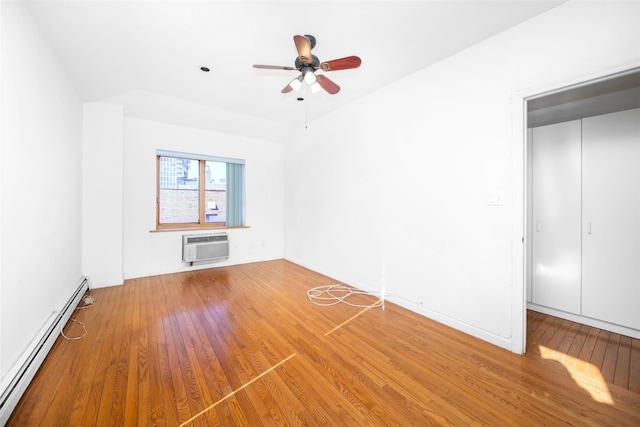 interior space with baseboard heating, ceiling fan, an AC wall unit, and hardwood / wood-style flooring