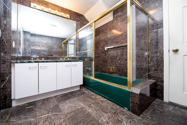 bathroom with tile walls, combined bath / shower with glass door, and vanity