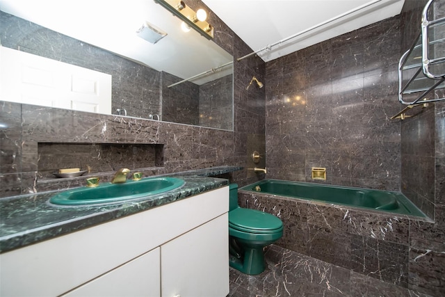 full bathroom with toilet, tile walls, vanity, and tiled shower / bath