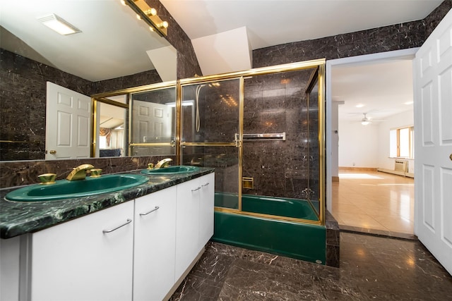 bathroom featuring ceiling fan, bath / shower combo with glass door, tile walls, and vanity