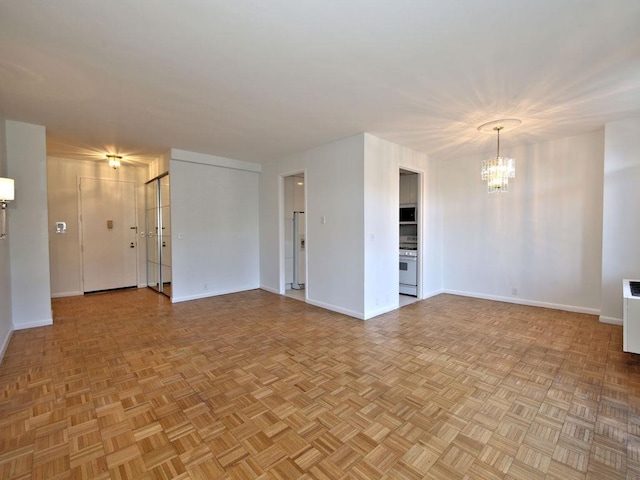 spare room featuring baseboards and a notable chandelier