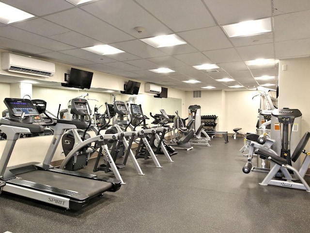 workout area featuring a wall unit AC and a paneled ceiling