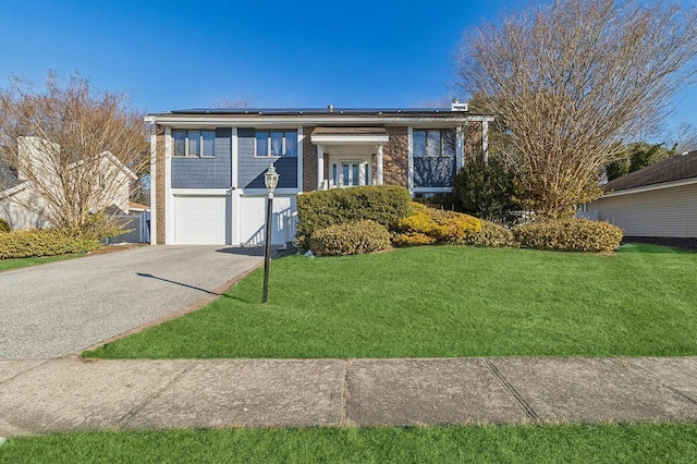 ranch-style house with aphalt driveway, a front yard, roof mounted solar panels, and brick siding