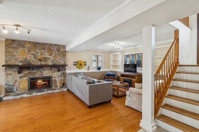 living room featuring a textured ceiling, ornamental molding, and a fireplace