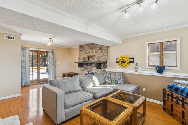 living area featuring light wood finished floors, a textured ceiling, visible vents, and crown molding