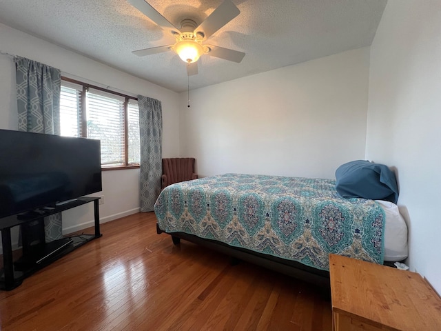bedroom featuring wood finished floors, a ceiling fan, and baseboards