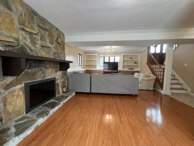 living room featuring a textured ceiling, wood finished floors, crown molding, and stairs