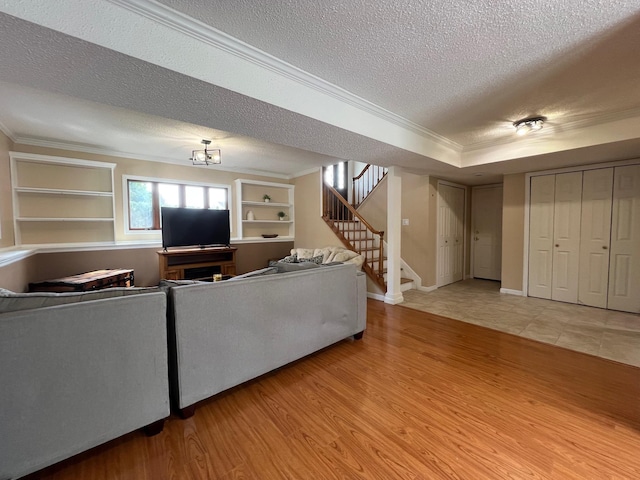 living room with crown molding, a textured ceiling, stairway, and wood finished floors