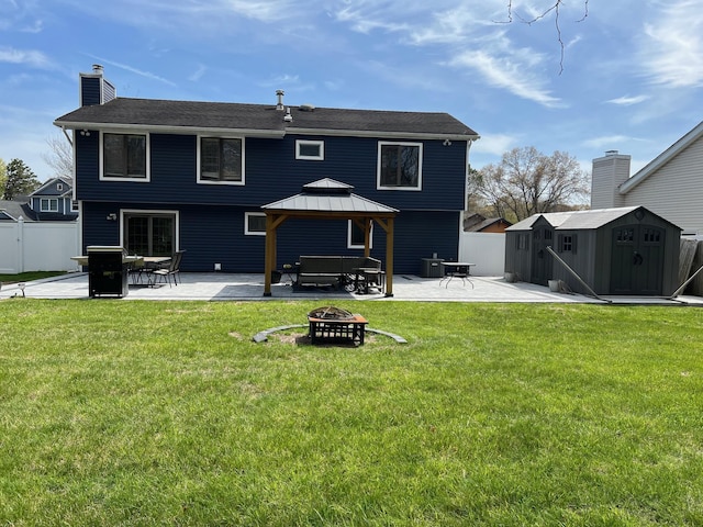back of house featuring a patio area, a gazebo, a storage unit, a fire pit, and fence
