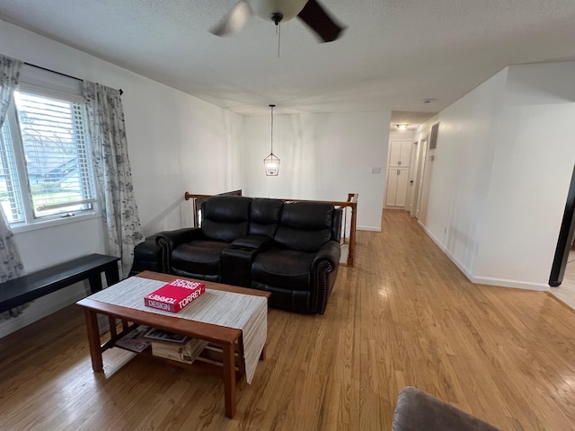 living room with a ceiling fan, baseboards, and light wood-style floors