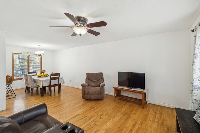 living area featuring baseboards, ceiling fan with notable chandelier, and light wood-style floors