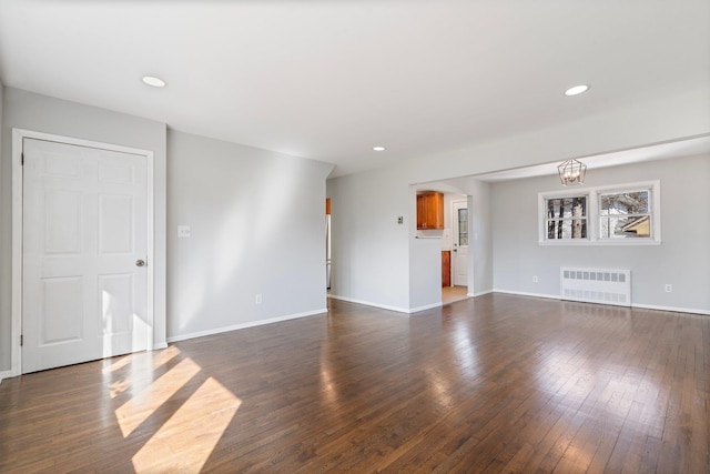 unfurnished living room with radiator heating unit, baseboards, dark wood finished floors, and recessed lighting