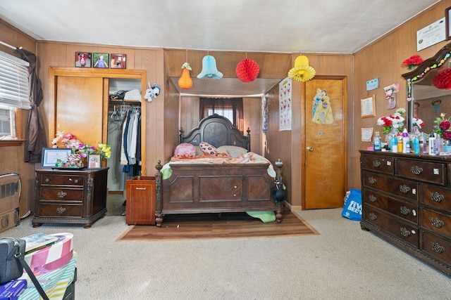 carpeted bedroom featuring wood walls and a closet