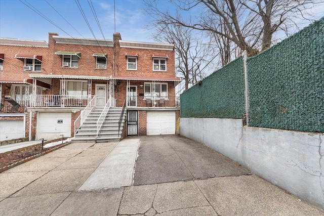 townhome / multi-family property featuring an attached garage, covered porch, brick siding, concrete driveway, and a chimney