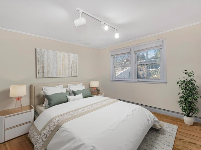 bedroom featuring ornamental molding, wood finished floors, and track lighting