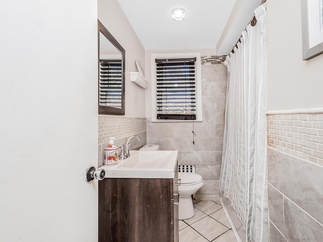 bathroom featuring tile patterned flooring, tile walls, toilet, and vanity