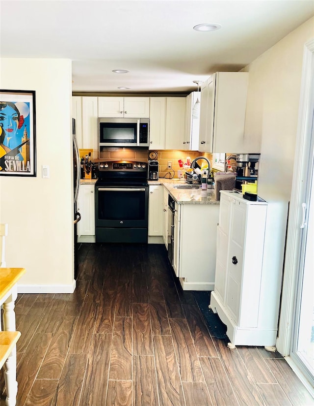 kitchen with white cabinets, dark wood-type flooring, stainless steel appliances, and a sink