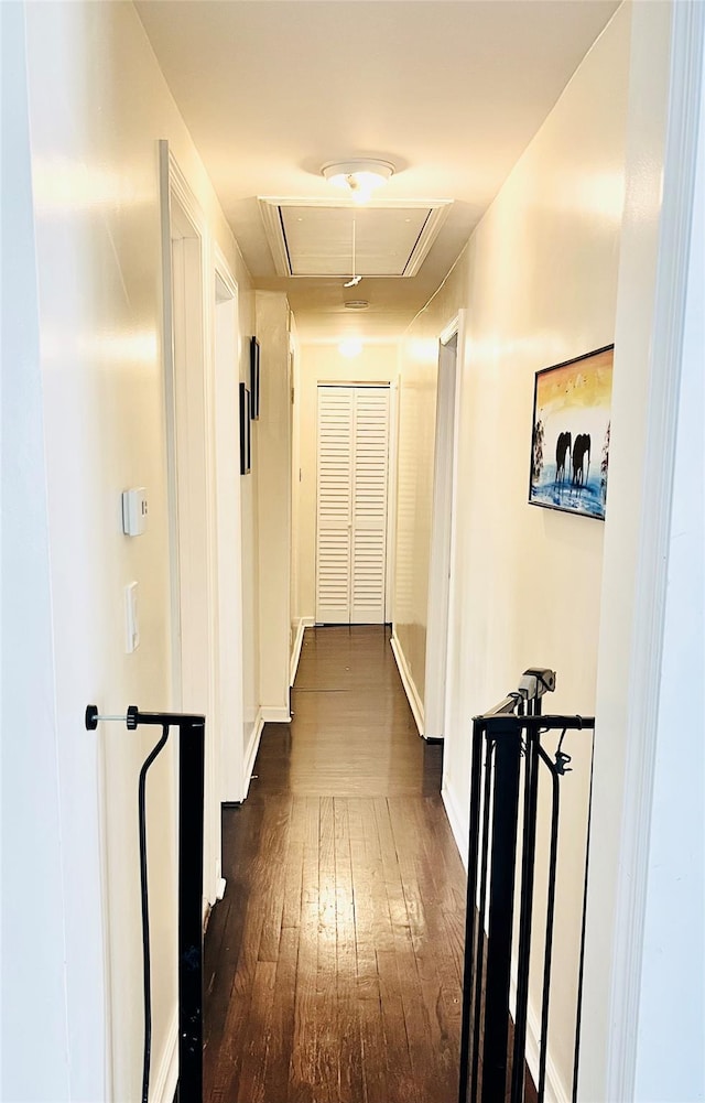 hall featuring attic access, baseboards, and dark wood-style floors